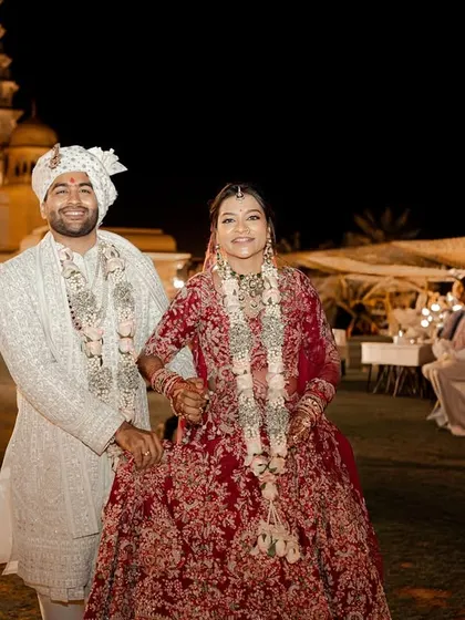 The newly married couple walks through their reception area, hand in hand. This candid shot captures the happy, relaxed atmosphere of the post-ceremony celebrations at their palace wedding.