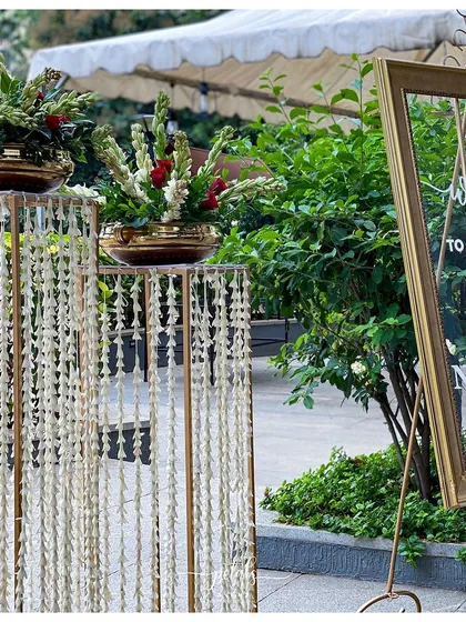 This elegant entrance features stands with hanging tuberose garlands and a modern transparent welcome sign, setting a magical tone for the wedding day.