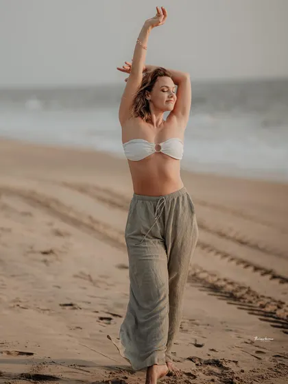 A beautiful, carefree moment on the beach. The model's pose and expression perfectly capture a feeling of freedom and connection with nature.