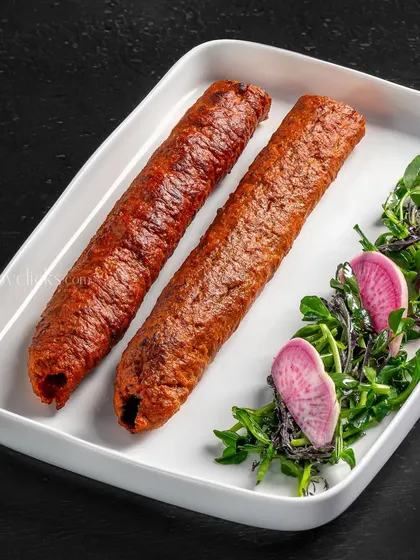 Seekh kebabs served with a side of microgreens and pickled radish, a clean and simple presentation.