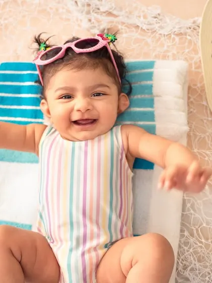 A big, happy grin from our little beach baby. Her tiny sunglasses and joyful expression are what summer dreams are made of.