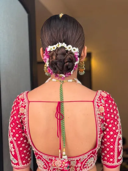 The back view of a classic floral bun, showing the neat wrap and the beautiful arrangement of fresh flowers. This is a popular choice for brides wanting a traditional yet fresh look.