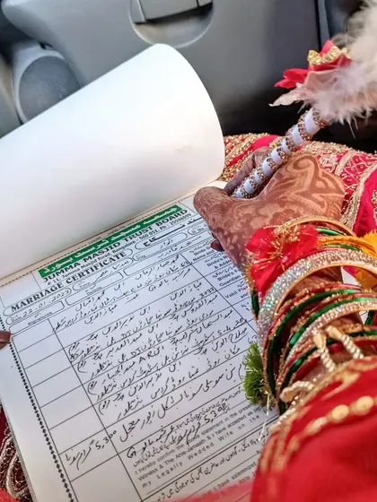 A close-up of the Nikkah-nama being signed, with the bride's intricate mehendi on full display.