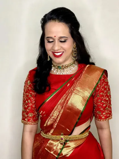 For Supravika's event, we went with a classic look featuring a bold red lip and soft golden eyeshadow. Her hair was styled in soft waves, half-up, to complement her elegant red silk saree.