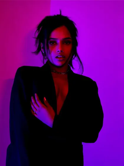 A direct, almost confrontational gaze from within the colored lights. This is a very powerful and modern portrait style.