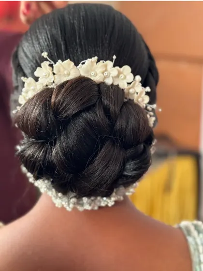 This intricate braided bun is a work of art. Adorned with beautiful white floral accessories, it's a stunning choice for a South Indian bride.
