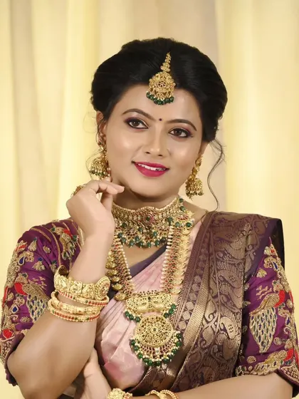 A smiling bridal portrait, highlighting the intricate details of the embroidered blouse and the complete jewelry set.