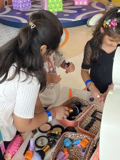 Two friends合作 on a makeover at the pretend makeup station during a party.