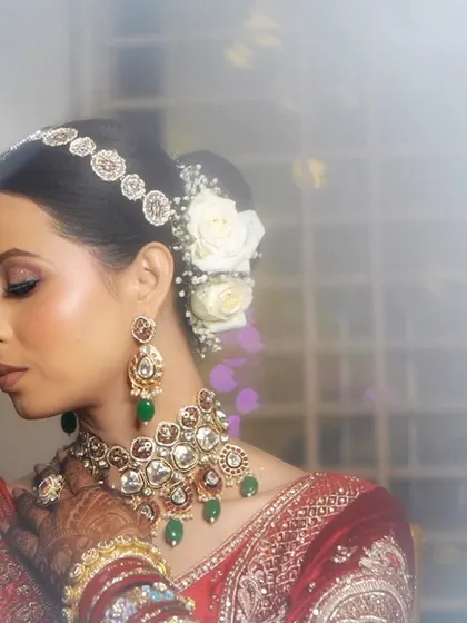 A dreamy, artistic portrait of a bride in her red lehenga. The white roses in her hair add a touch of modern elegance to the traditional look.
