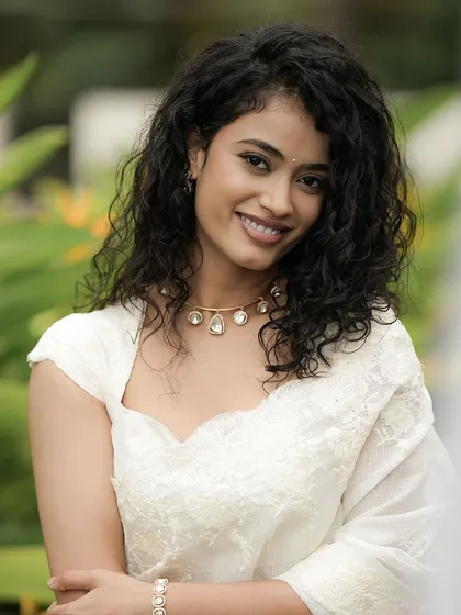 A happy, smiling portrait that showcases her natural curls and the fresh, clean makeup.