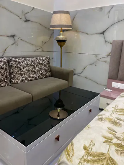 A closer look at the seating area. The combination of a solid color sofa with patterned cushions and a classic floor lamp creates a warm and inviting corner.