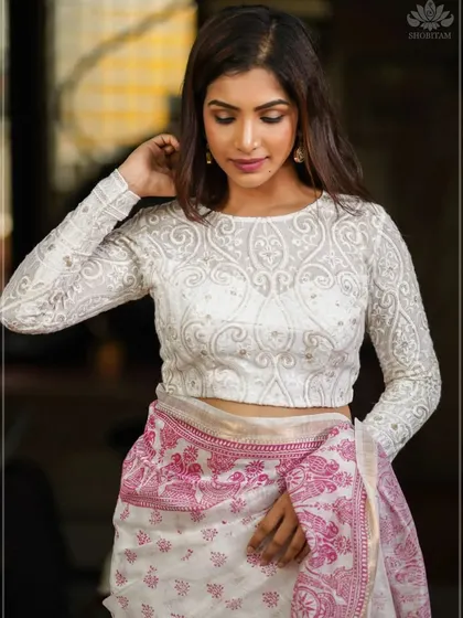 This white blouse features long, sheer sleeves with intricate all-over embroidery, offering a look of pure elegance.