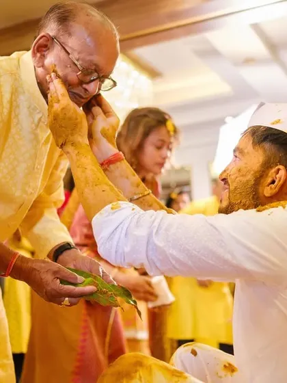 A heartwarming moment as the groom applies haldi to an elder's face, showing respect and love during the ceremony.