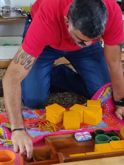 A parent deeply engaged with a set of Montessori math materials. Our workshops give you the chance to see how these beautiful, intelligent materials lead a child from concrete quantities to abstract understanding.