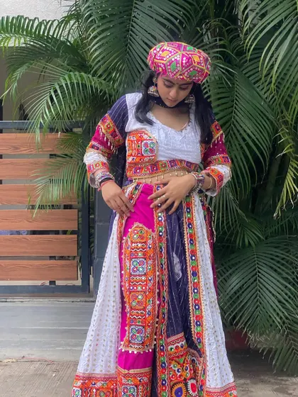 A unique Garba outfit featuring dhoti-style pants with a heavily embroidered top and a matching pagdi.