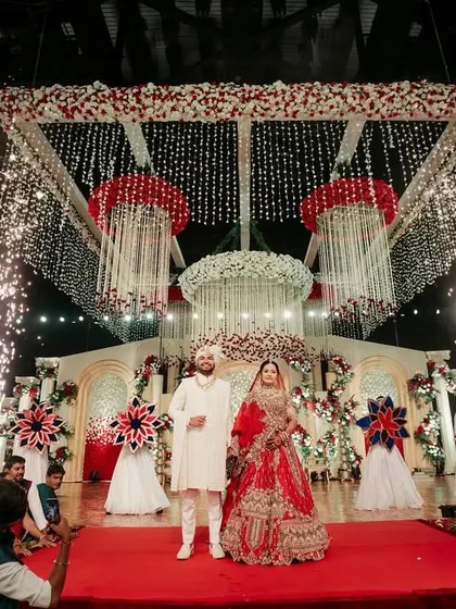 Crafting the grand varmala moment with meticulous planning. Here, the couple stands on a grand stage, framed by pyrotechnics, ready for their big moment.