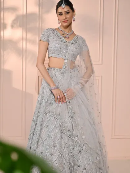 A full-length portrait of the modern bride. The intricate silver lehenga is the centerpiece, with the makeup providing a soft, elegant frame for her beauty.