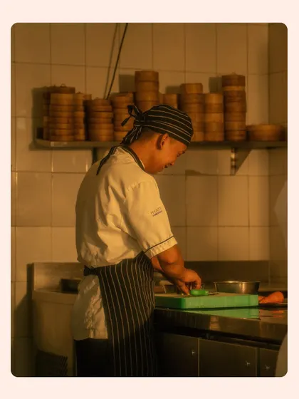 A candid shot of a chef prepping ingredients in the background. Images like this add authenticity and show the foundation of fresh ingredients that go into every meal.