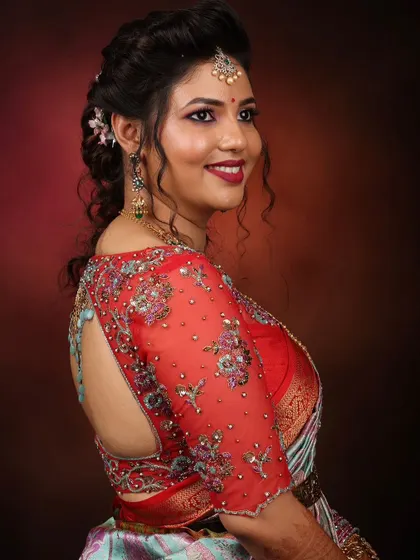 A stunning reception look. This bride's red blouse features sheer sleeves with intricate, multi-colored floral embroidery and a keyhole back.