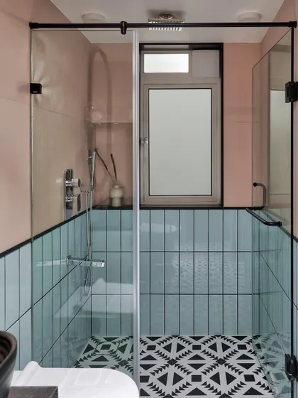 The daughters had a fun request for their bathroom: something quirky. We used patterned black and white tiles for the floor, with mint subway tiles on one wall and blush pink on the other, creating a unique and playful design.