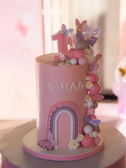 A professional shot of this tall, elegant first birthday cake.
