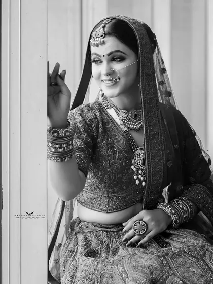 A timeless black and white portrait of the bride by a window. The natural light creates a soft and classic feel, highlighting her silhouette and joyful expression.