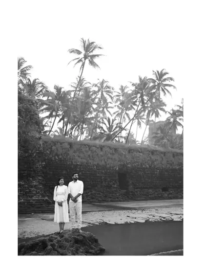 A dramatic black and white landscape portrait from a beach pre-wedding shoot. The stark contrast and wide angle emphasize the beautiful coastal scenery.