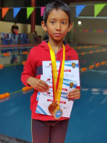 Reet Kokatanur, one of our junior champions, holding his three gold medals from the non-medalist swimming competition in freestyle, backstroke, and kickboard events.