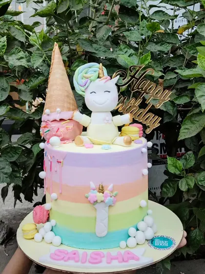 A whimsical cake combining two childhood favorites: unicorns and ice cream. This pastel rainbow cake features a happy unicorn enjoying a giant ice cream cone.