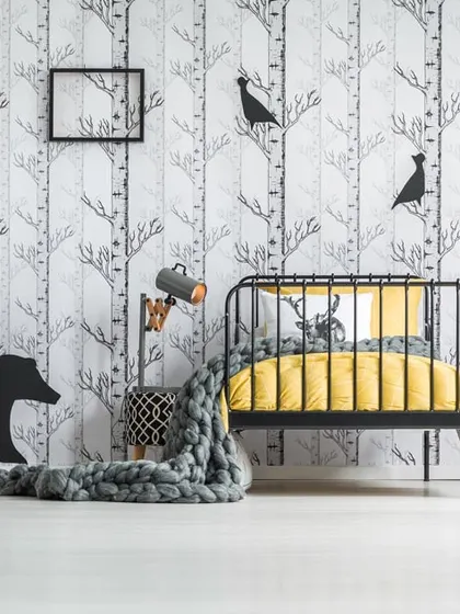 A stylish and modern kids' room featuring a black and white birch tree wallpaper. This versatile design can grow with your child and pairs well with colorful furniture and decor.