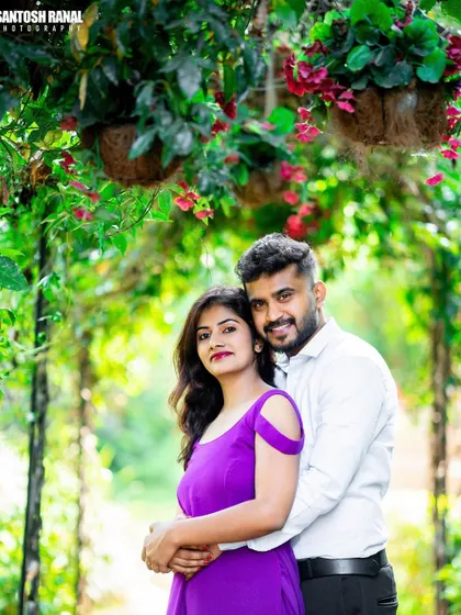 A bright and happy portrait of a couple framed by a lush floral archway.