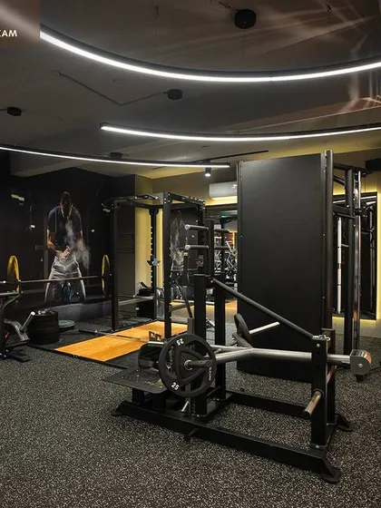 In this section of the gym, we used a textured orange pillar as a vibrant accent piece. It adds a splash of color and visual interest among the professional-grade weight machines and custom wall graphics.