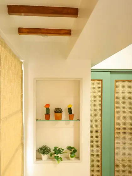 A small niche with decorative cacti adds a playful touch, complemented by the wooden beams on the ceiling.
