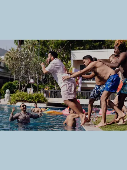 Friends team up to throw a guest into the pool, a perfect example of the fun at a destination wedding.