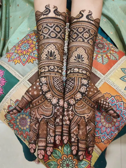 Another look at a classic bridal design, this time against a colorful cushion. You can see the fine details of the peacock borders and the lotus motifs within the jharokha-style windows on the arms.