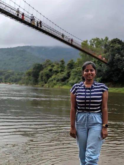 A traveler posing by the river near the hanging bridge on the Netravathi trip.