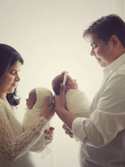 A closer view of the parents with their newborn twins. This shot highlights the babies' tiny features as they are held securely by their loving parents.