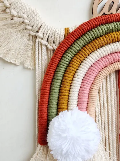 A detail shot of the custom rainbow and pompom cloud. The craftsmanship in the wrapped rainbow and the fluffy pompom shows the love put into it.