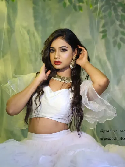A beautiful portrait of a model in a white two-piece outfit with ruffled sleeves, set against a dreamy green backdrop.
