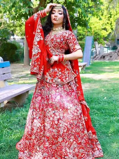 A classic red bridal lehenga with all-over floral embroidery. This timeless piece is perfect for outdoor photoshoots and is available to rent.