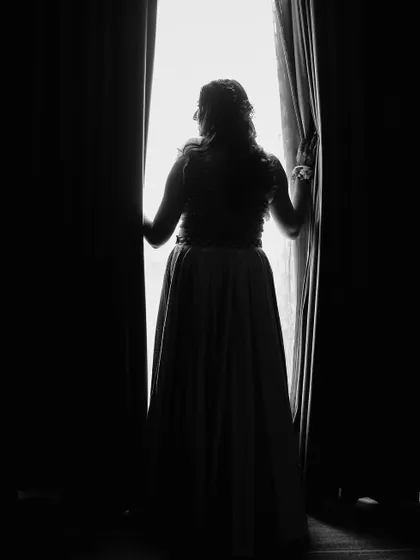 An artistic silhouette of the bride looking out a window, creating a sense of anticipation.