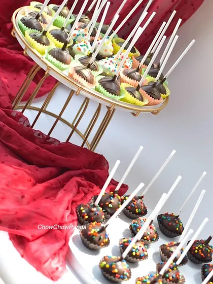 Here is a large order of cake pops ready for a party dessert table. This set includes a variety of chocolate-dipped pops, some with colourful sprinkles and others with a simple chocolate drizzle.
