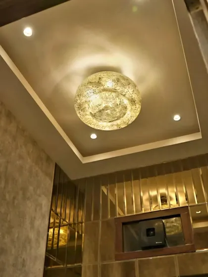 The "moon" chandelier casts a warm, diffused glow, adding to the sophisticated ambiance of the powder room.