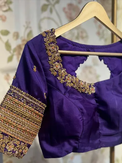 A simple yet elegant purple blouse with multi-colored threadwork on the sleeves, perfect for a classic silk saree.