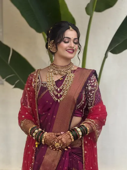 A joyful candid moment of bride Vaibhavi. Her look is enhanced with a red sheer dupatta, layered gold necklaces, and a smile that shows how comfortable and happy she feels.