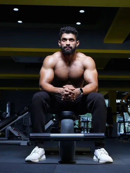 A moment of rest and reflection on a workout bench. Even in a seated position, you can see the muscle fullness in the chest and arms that comes from consistent training.