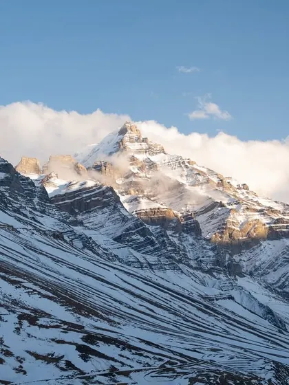 A collection of breathtaking landscapes from Spiti. These images feature the majestic snow-capped peaks, the turquoise river, and the dramatic, winding roads carved into the mountainside.