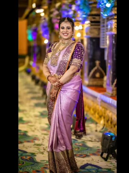 A full-length view of Anusha's naming ceremony outfit. The rich purple embroidered blouse stands out beautifully against the light lavender Kanjeevaram silk saree.