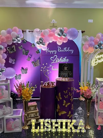 Here’s how I can bring a beautiful butterfly theme into your living room. This intimate home setup features a lovely balloon arch in pastel pink and purple, a personalized backdrop, and light-up marquee letters, proving you don’t need a huge venue for a stunning party.