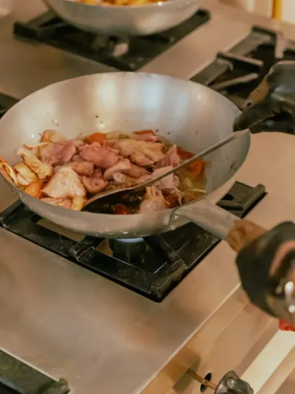A close-up of chicken being stir-fried in a wok. This high-heat cooking method is essential for many of our signature dishes.